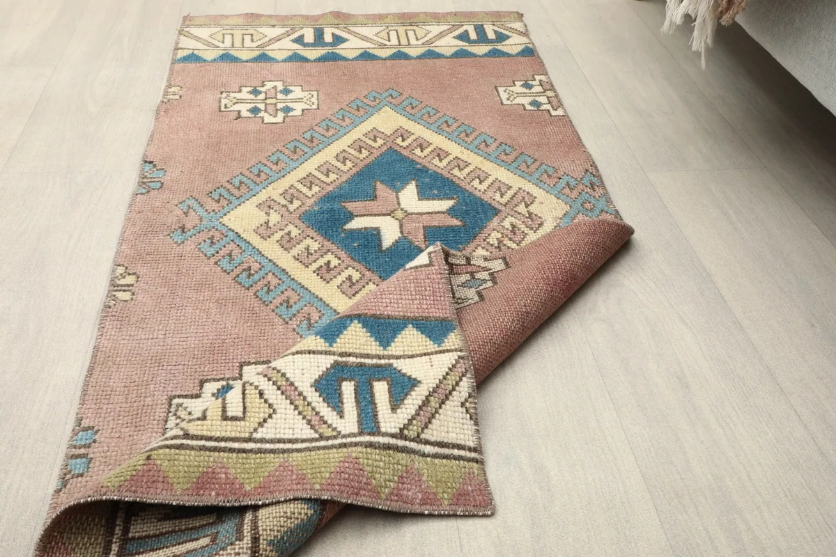 The rug partially folded over, displaying the full design and the flexibility of the vintage textile.