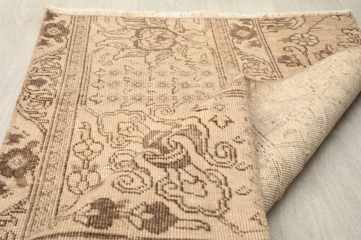 Angled view of the rug with one side folded to show the back and weave