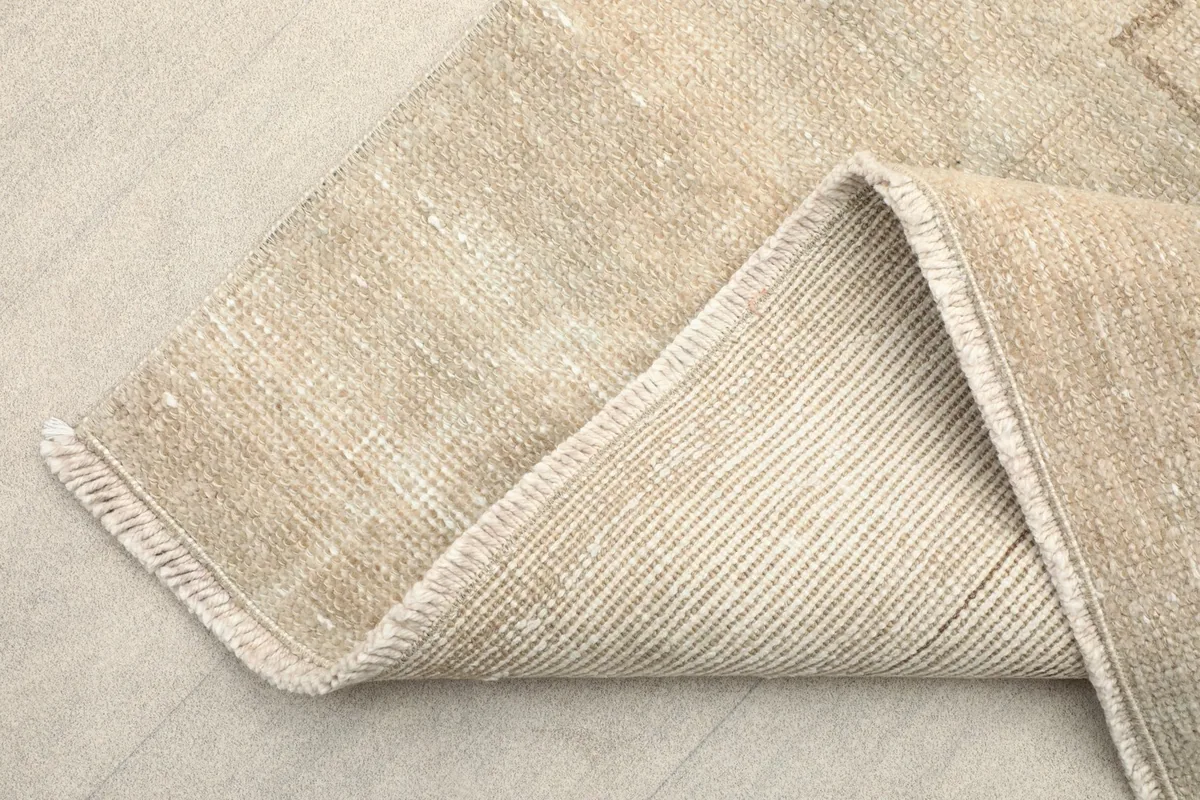 Corner of the runner rug folded back, revealing the cotton foundation and fringes