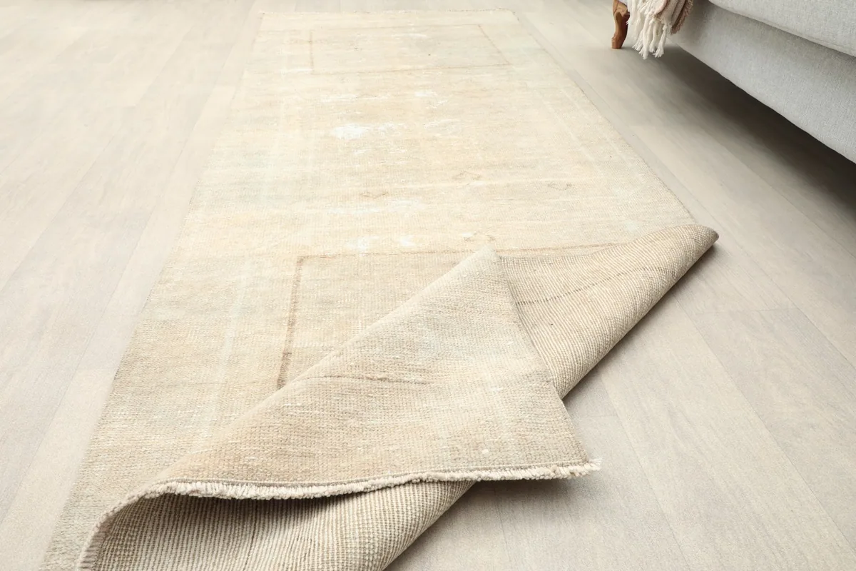 Runner rug partially rolled up, displaying the back and the low pile