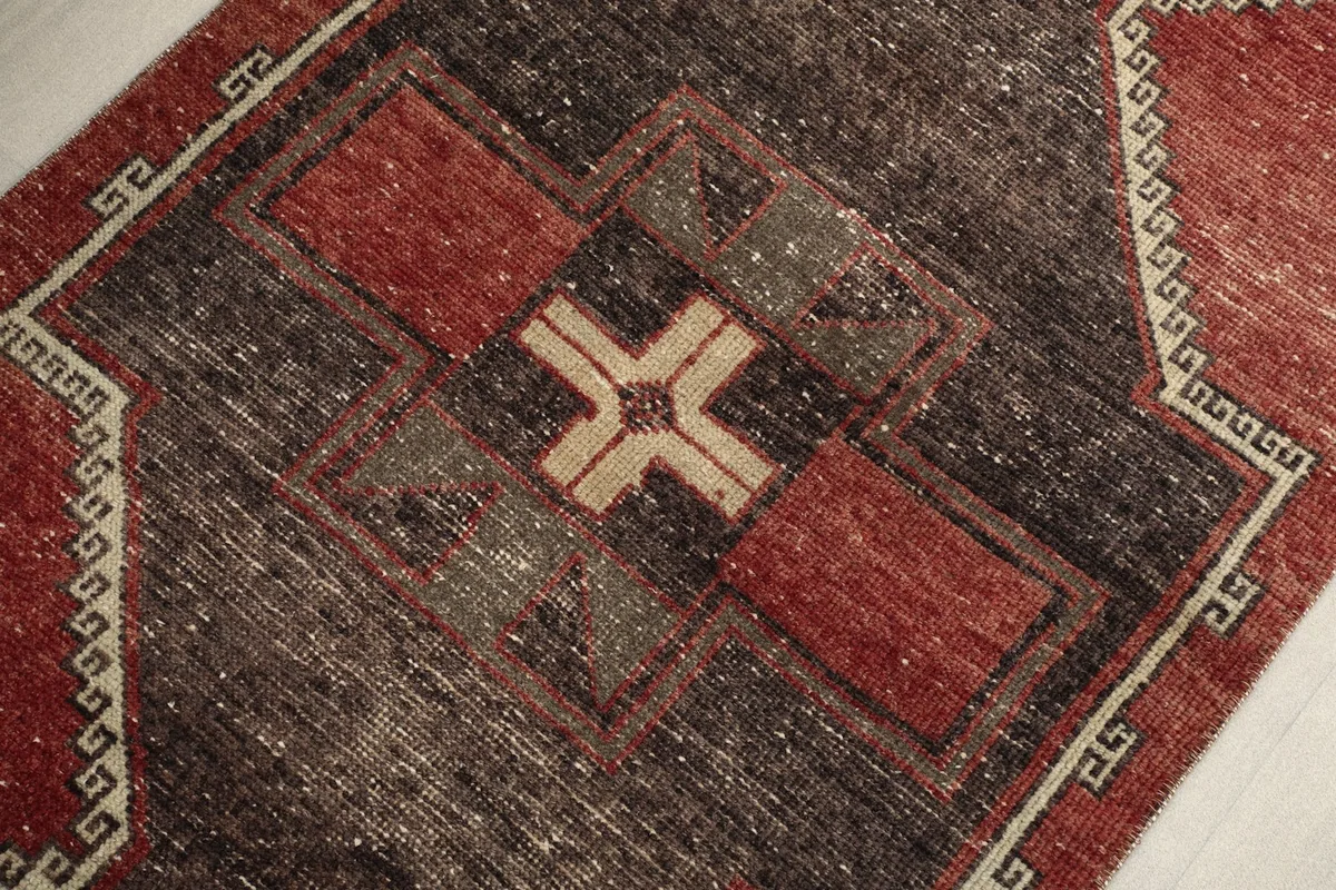 Close-up of the central charcoal geometric pattern with beige and red accents in the vintage rug