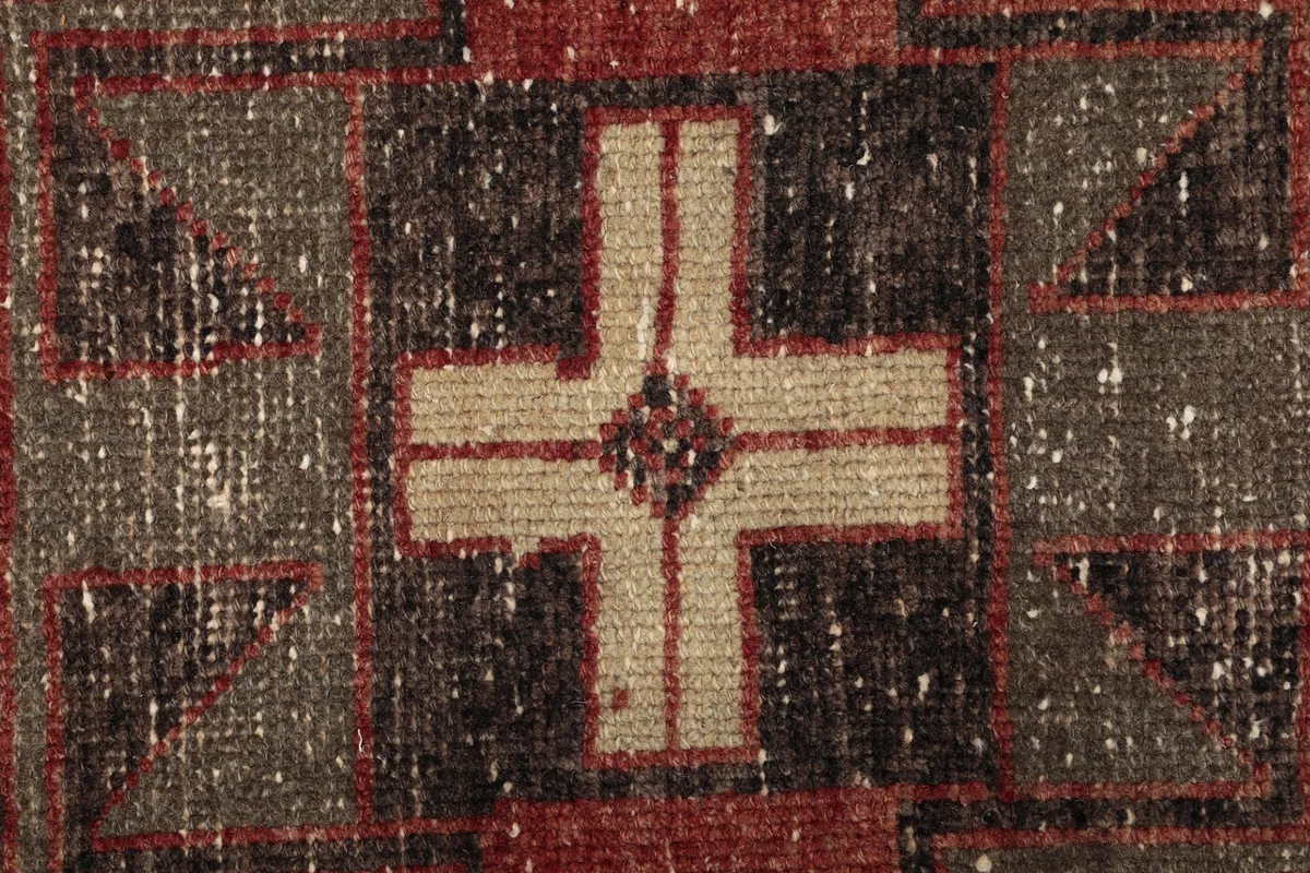 Detailed view of the intricate hand-knotted weave and central cross-like motif within the pattern