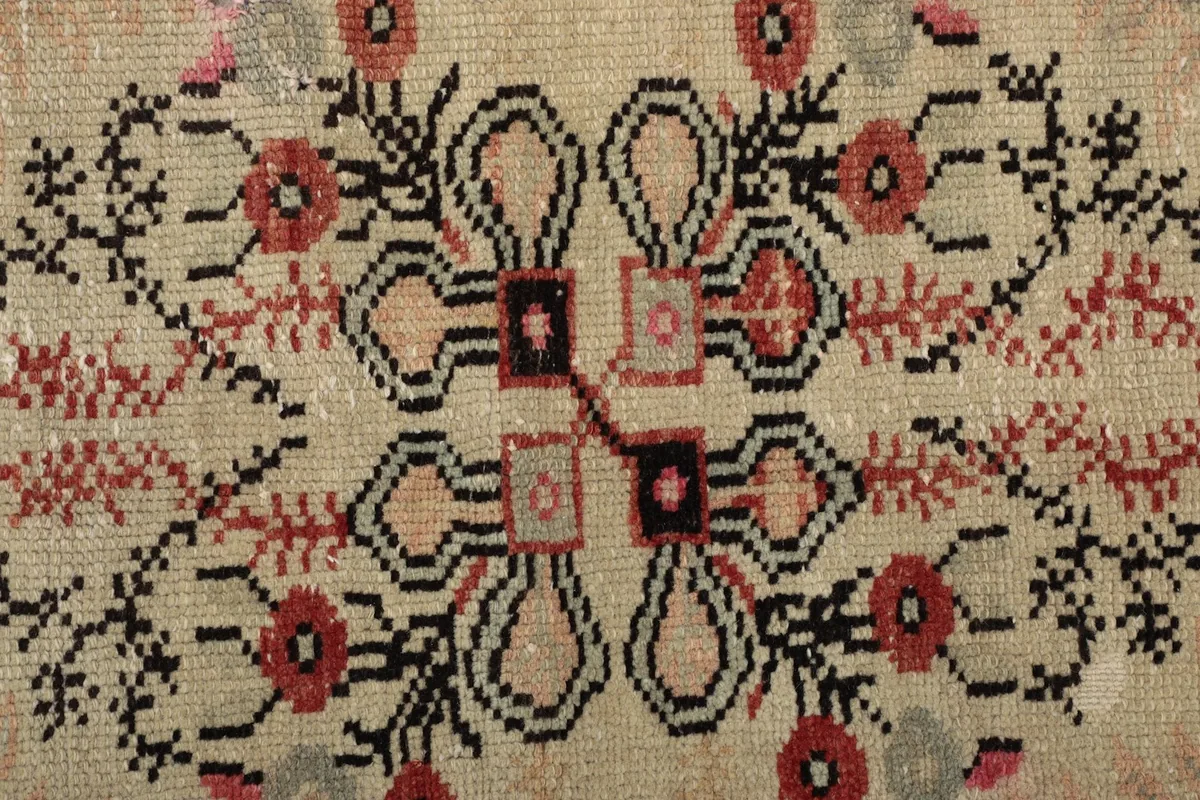 Extreme close-up of the hand-knotted wool pile within the ivory medallion, showing texture and colors.