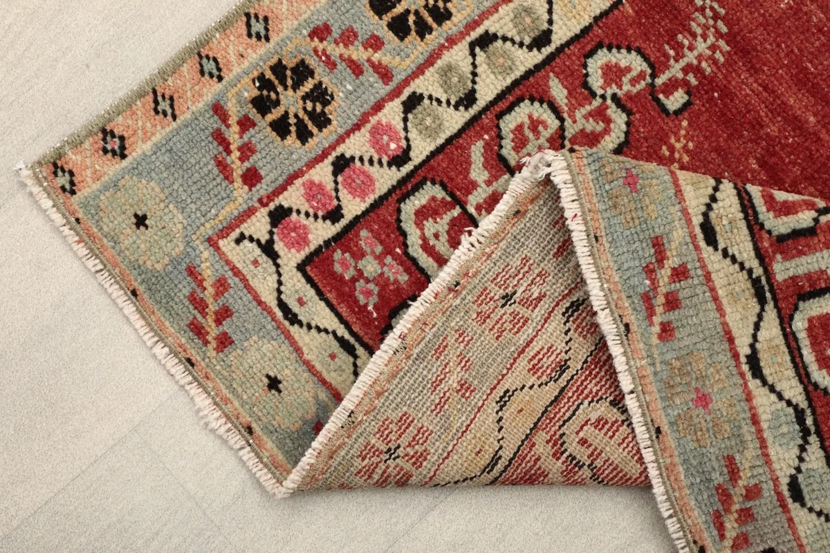 Folded corner of the rug, revealing the woven back and the details of the border design.