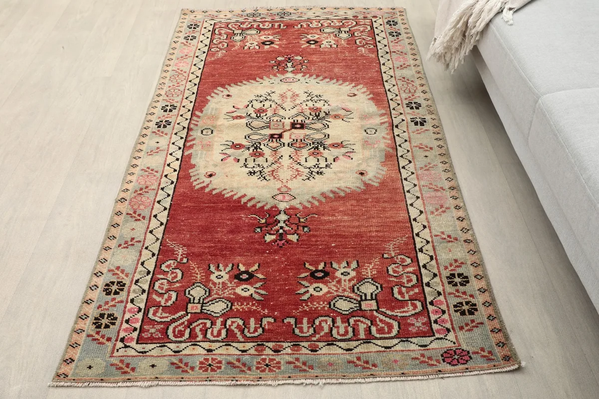 Overhead view of the red and ivory rug in a room setting, showing its rich colors and design.