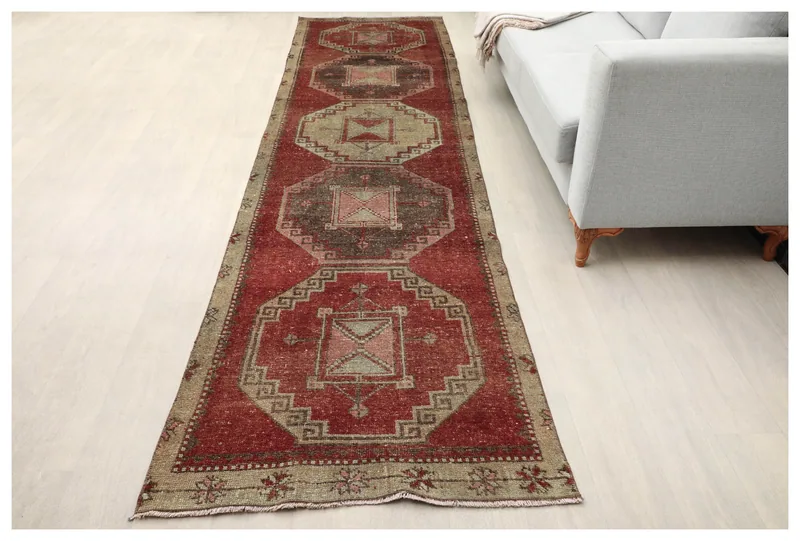 Full overhead view of the red and beige tribal geometric vintage runner rug on a white floor.