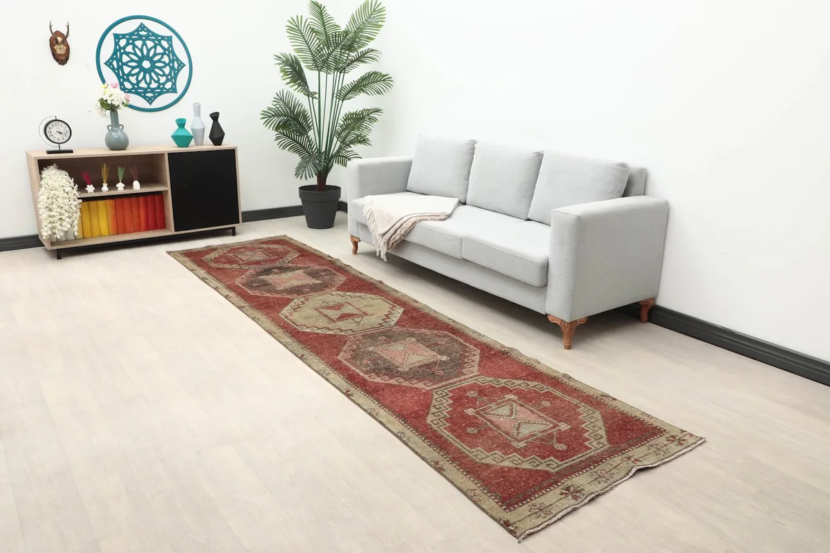 Vintage Anatolian runner rug displayed in a living room setting next to a gray sofa.