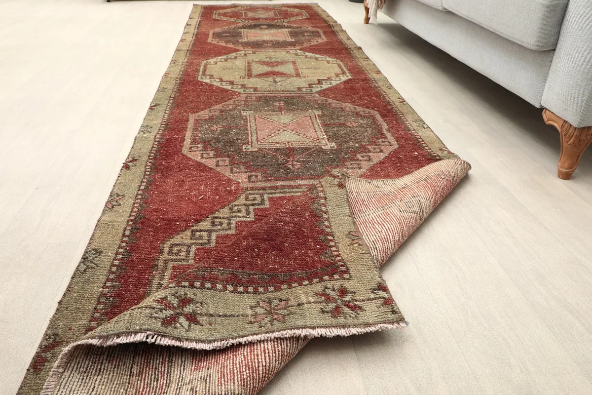 Partial view of the runner rug with one end folded back, showing its texture and construction.