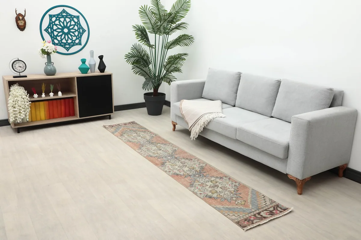 Rust and gray geometric runner rug placed in a modern living space next to a gray sofa.