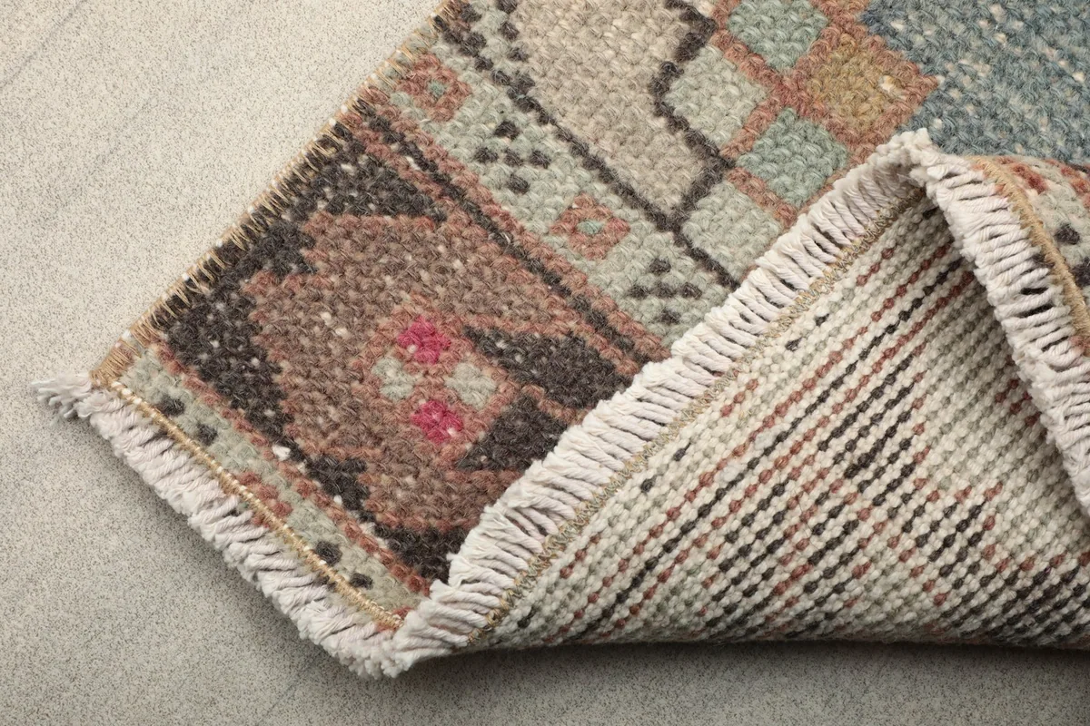 Corner view showing the back of the hand-knotted rug, revealing the cotton foundation and fringe.