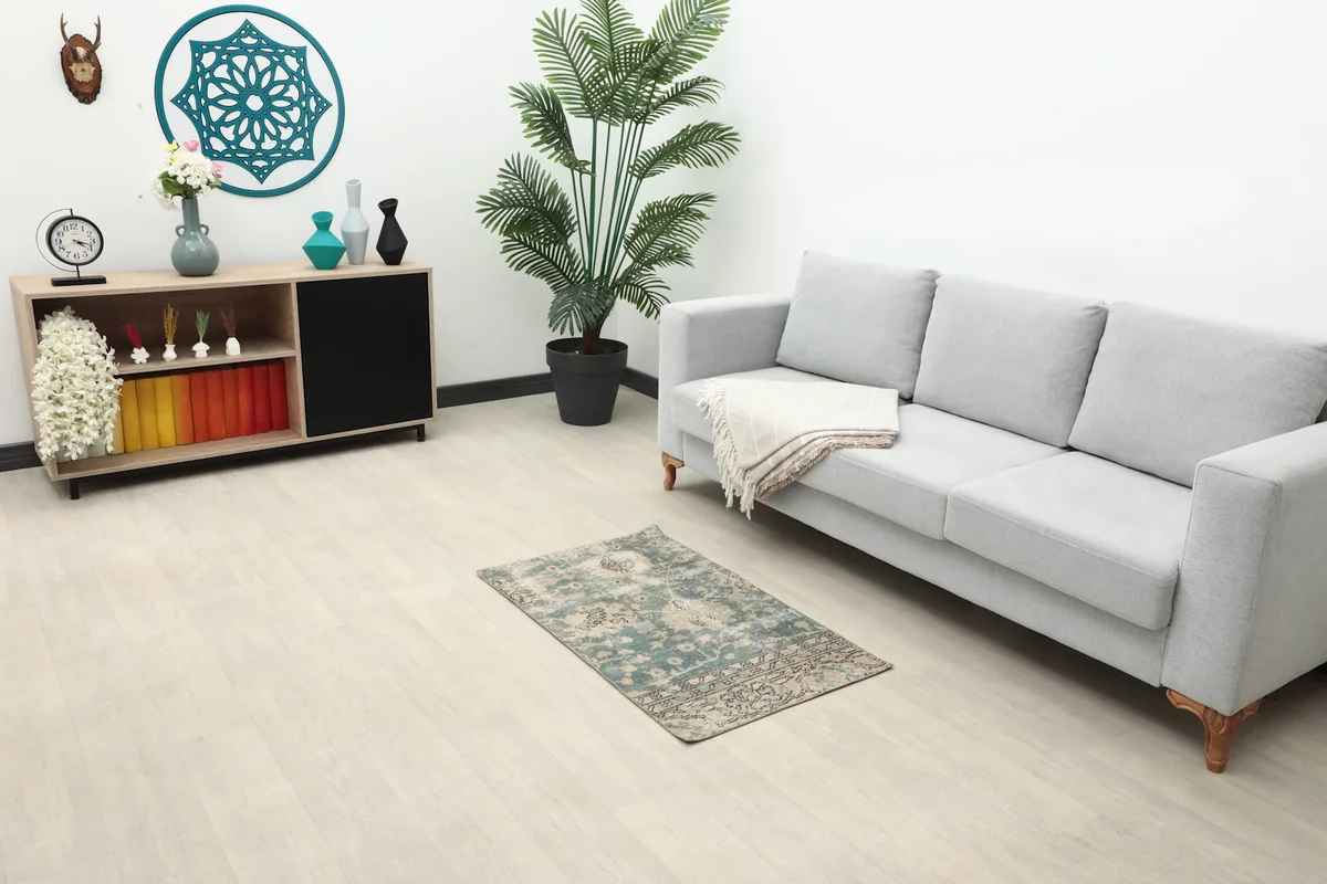 Vintage green and tan rug placed in a living room setting under a sofa
