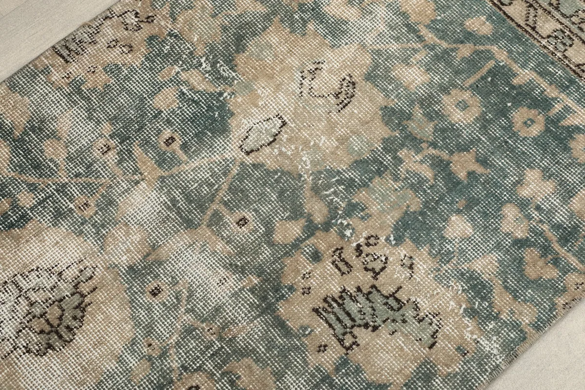 Close-up of the rug's distressed pile, highlighting the green and tan color variations
