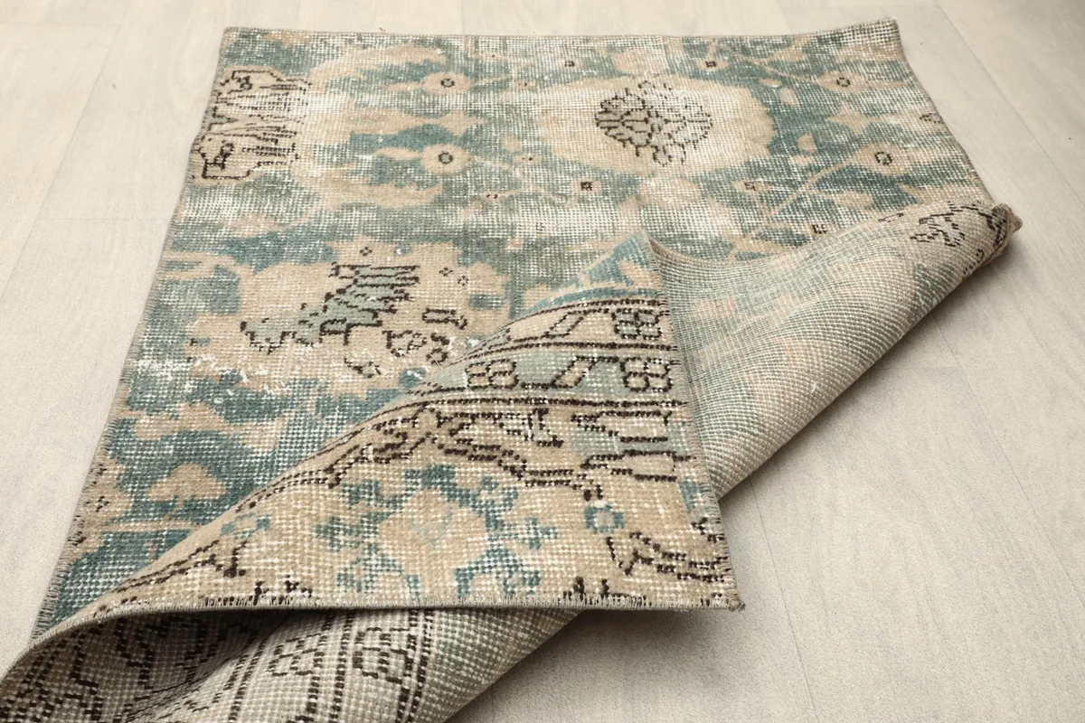 The rug folded to show both the top surface with green and tan patterns and the underside