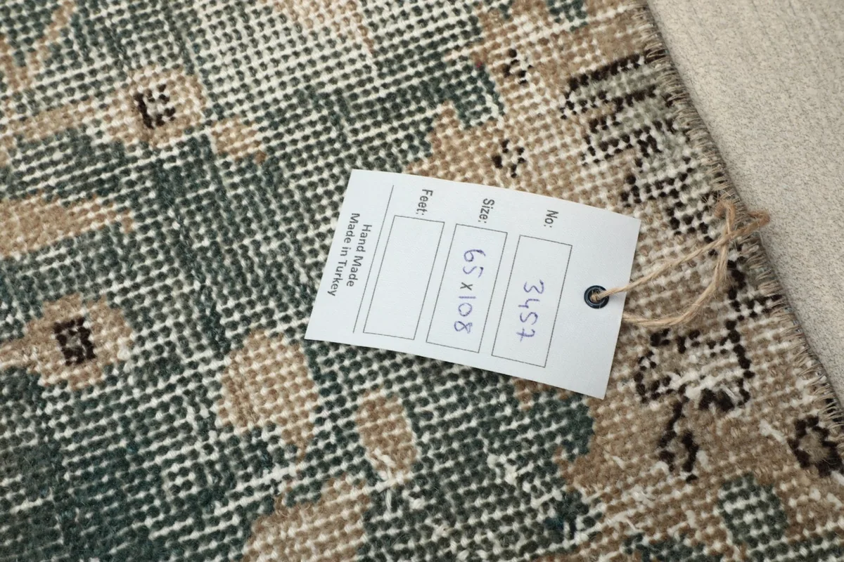 Close-up of the rug's surface with a tag displaying its dimensions (65x108 cm)