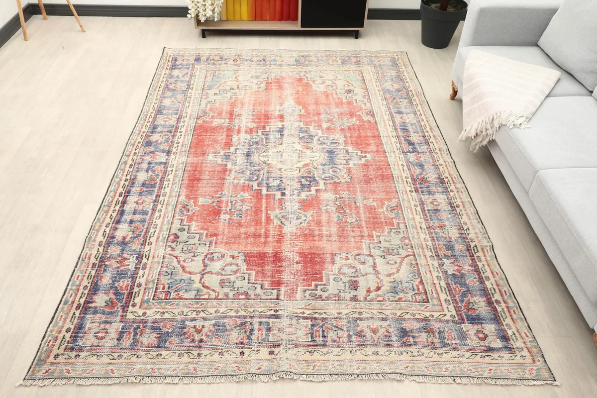 Vintage red and navy rug displayed in a living room setting with a light-colored sofa.