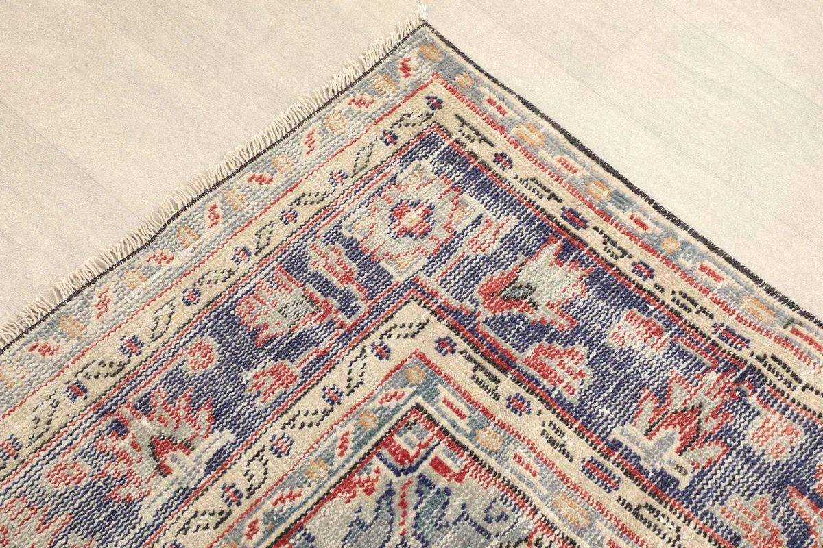 Corner detail of the rug, showing the navy border with geometric and floral motifs.