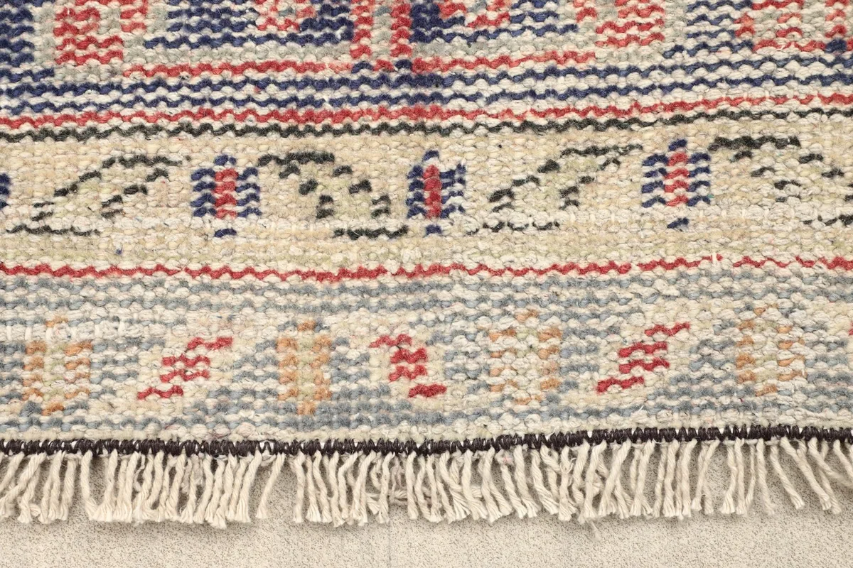Close-up detail of the rug's fringe and the intricate patterns along the border.