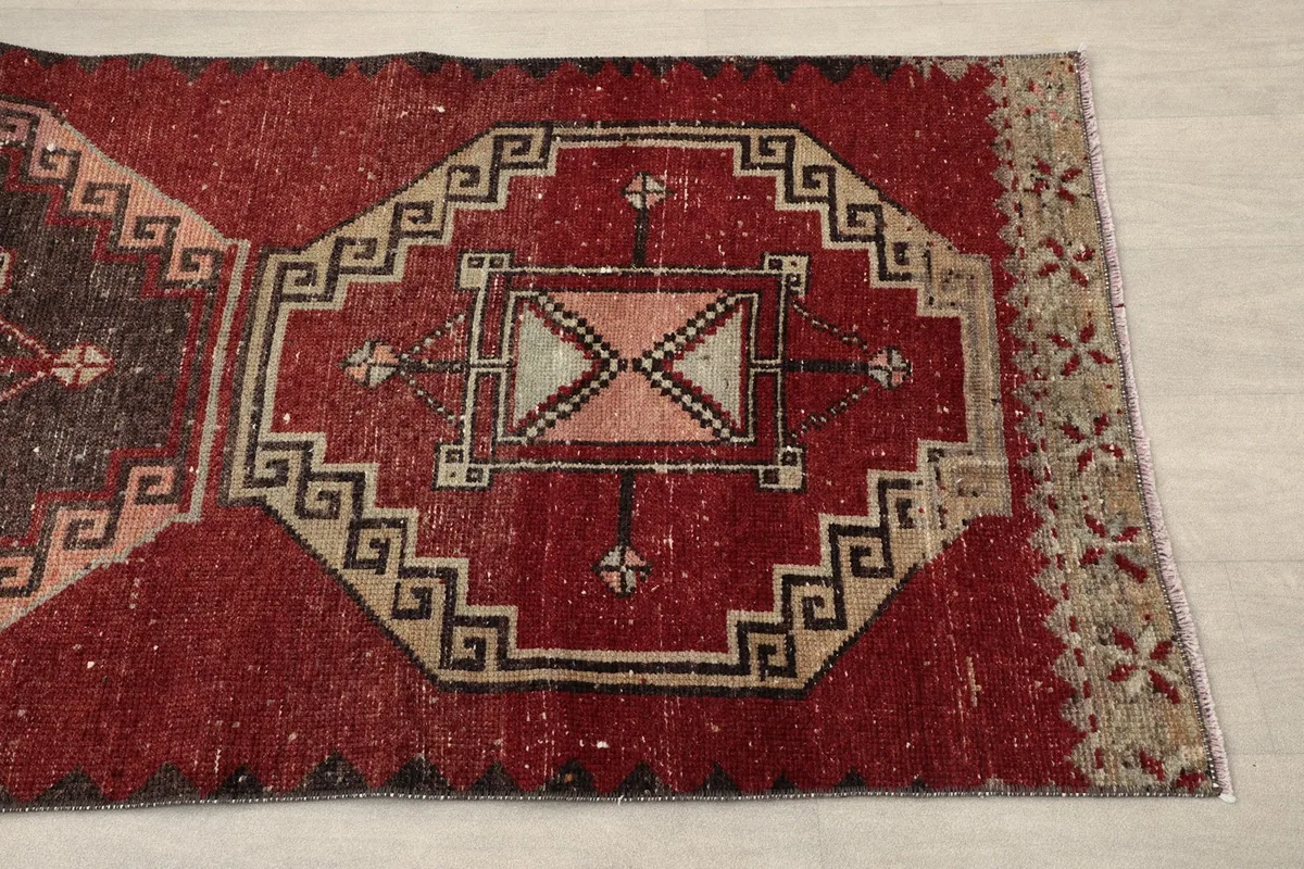 Close-up of a geometric medallion and part of the red field, showing texture and color variation