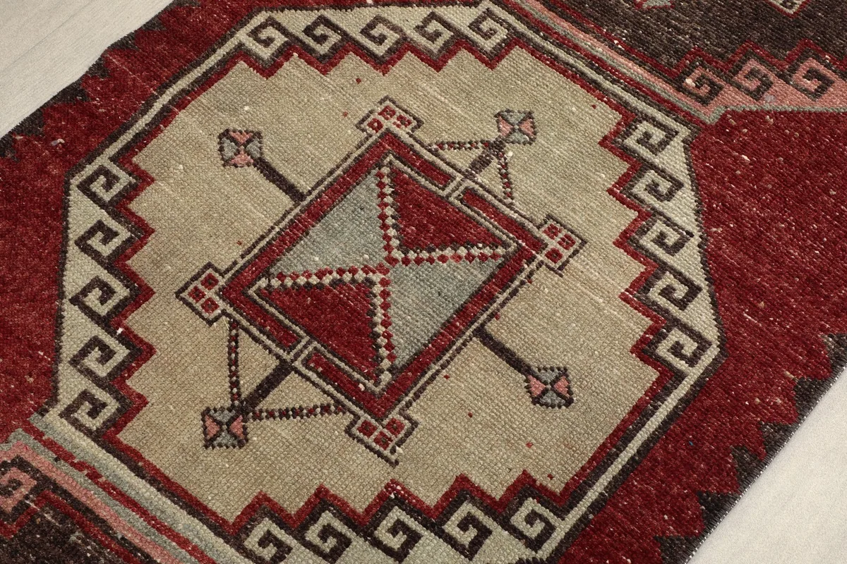 Close-up on a central geometric medallion with beige, red, and gray elements, showing knot detail