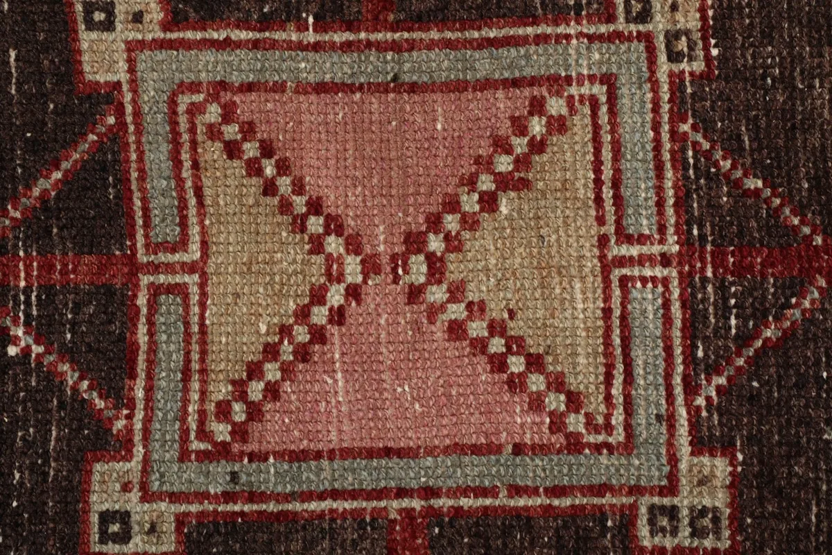 Extreme close-up of a pink and gray geometric motif within a medallion, revealing the wool pile