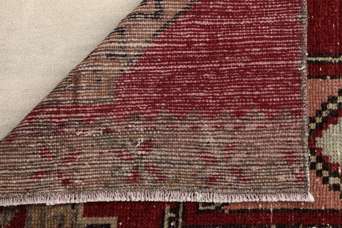 Corner of the rug folded to show the hand-knotted cotton foundation and wool pile reverse