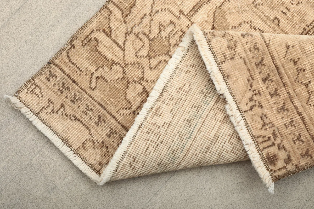 Close-up view of the back of the hand-knotted wool rug, showing the cotton foundation and fringe.