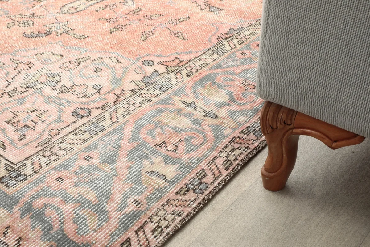 Close-up of the rug's border and field patterns next to a furniture leg