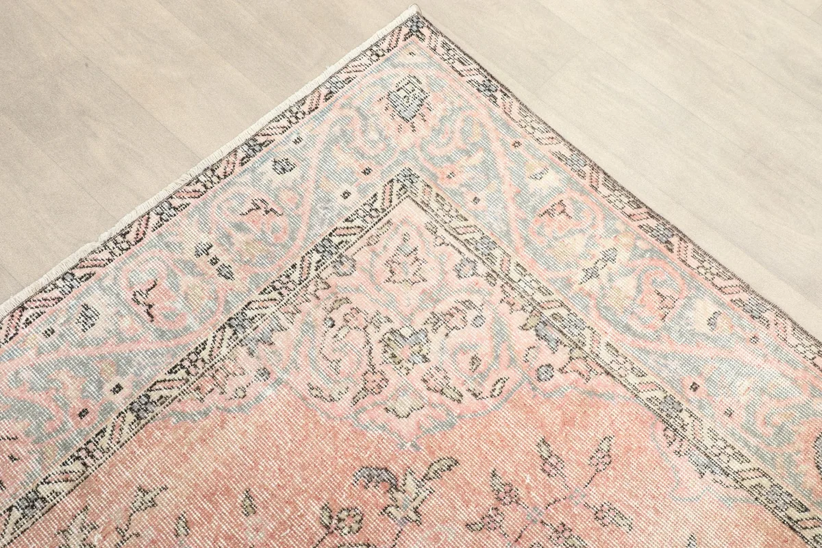 Detailed view of the corner of the rug, showing the intricate gray and rose border design