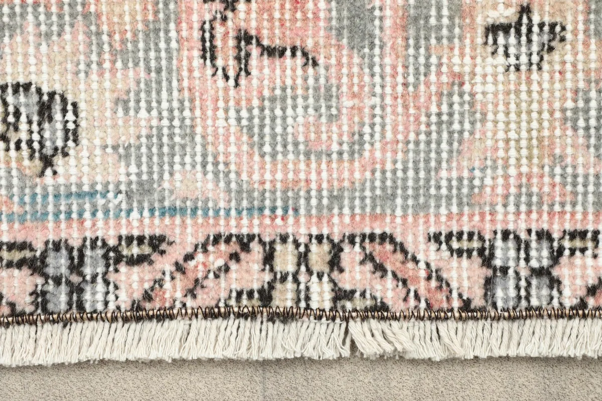 Close-up detail of the fringe and the patterned border of the hand-knotted wool rug