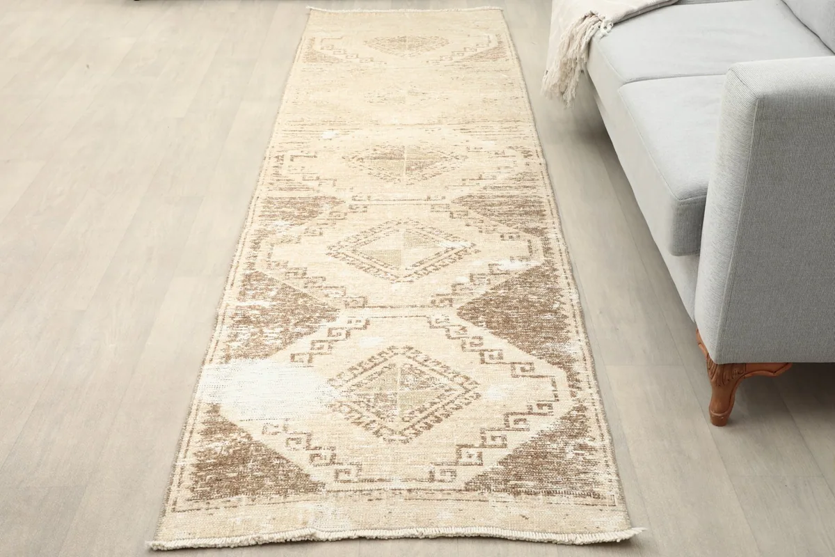 Beige and brown vintage runner placed in a room next to a light gray sofa