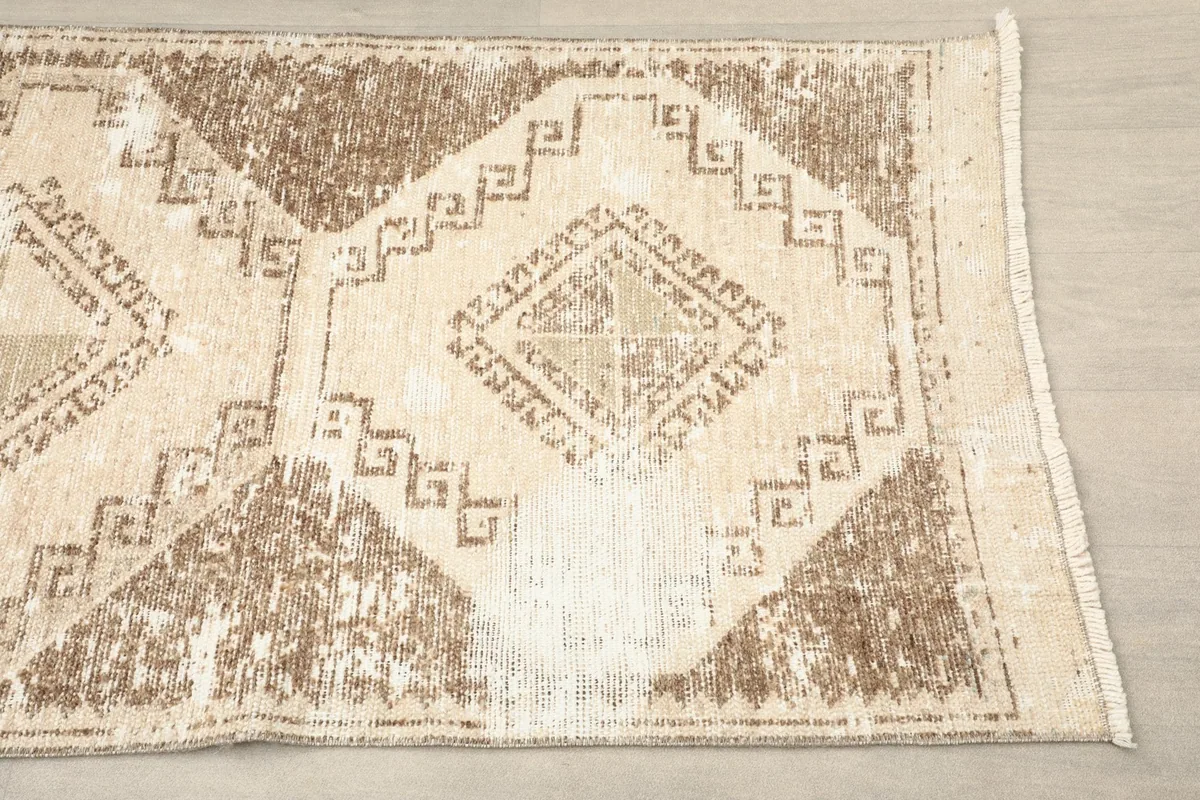 Close-up view of the beige and brown geometric patterns and border of the vintage runner