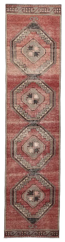 Full top view of a vintage Anatolian runner rug with rust field and geometric medallions on a white background.