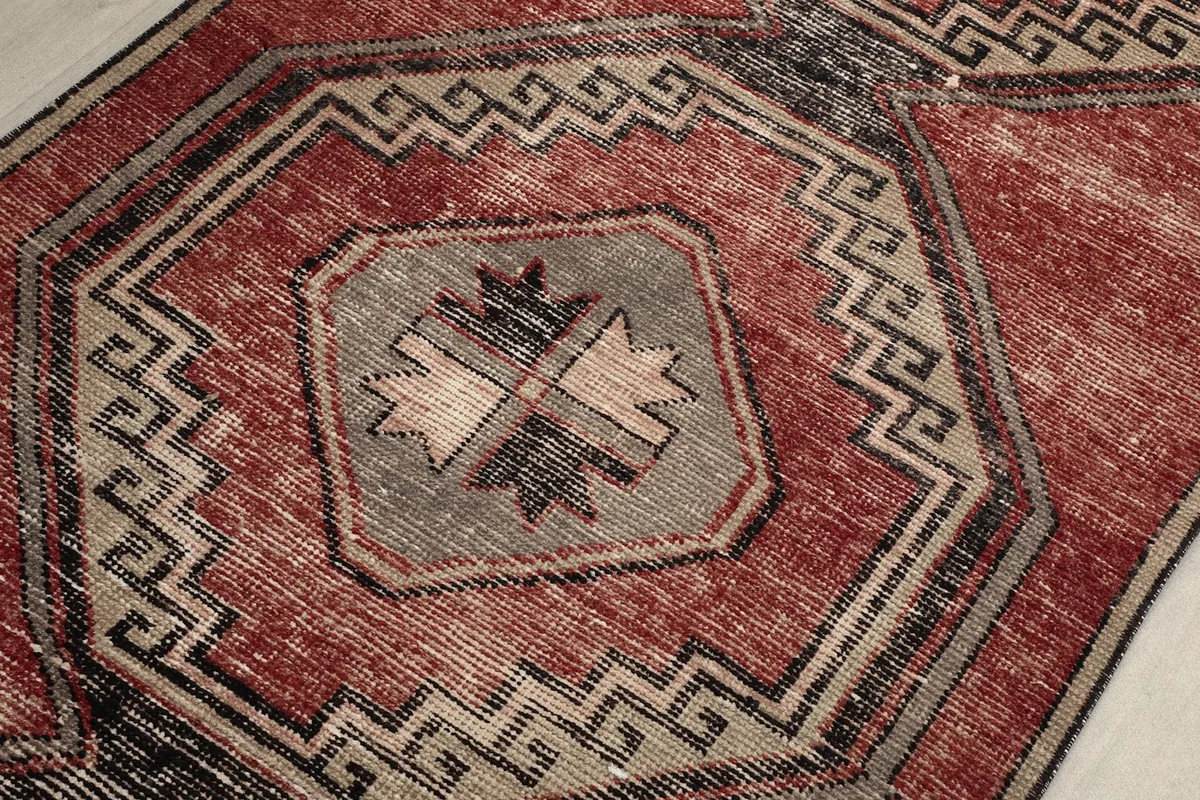 Detailed view of a central geometric medallion on the rust runner, highlighting the gray, black, and beige tones.