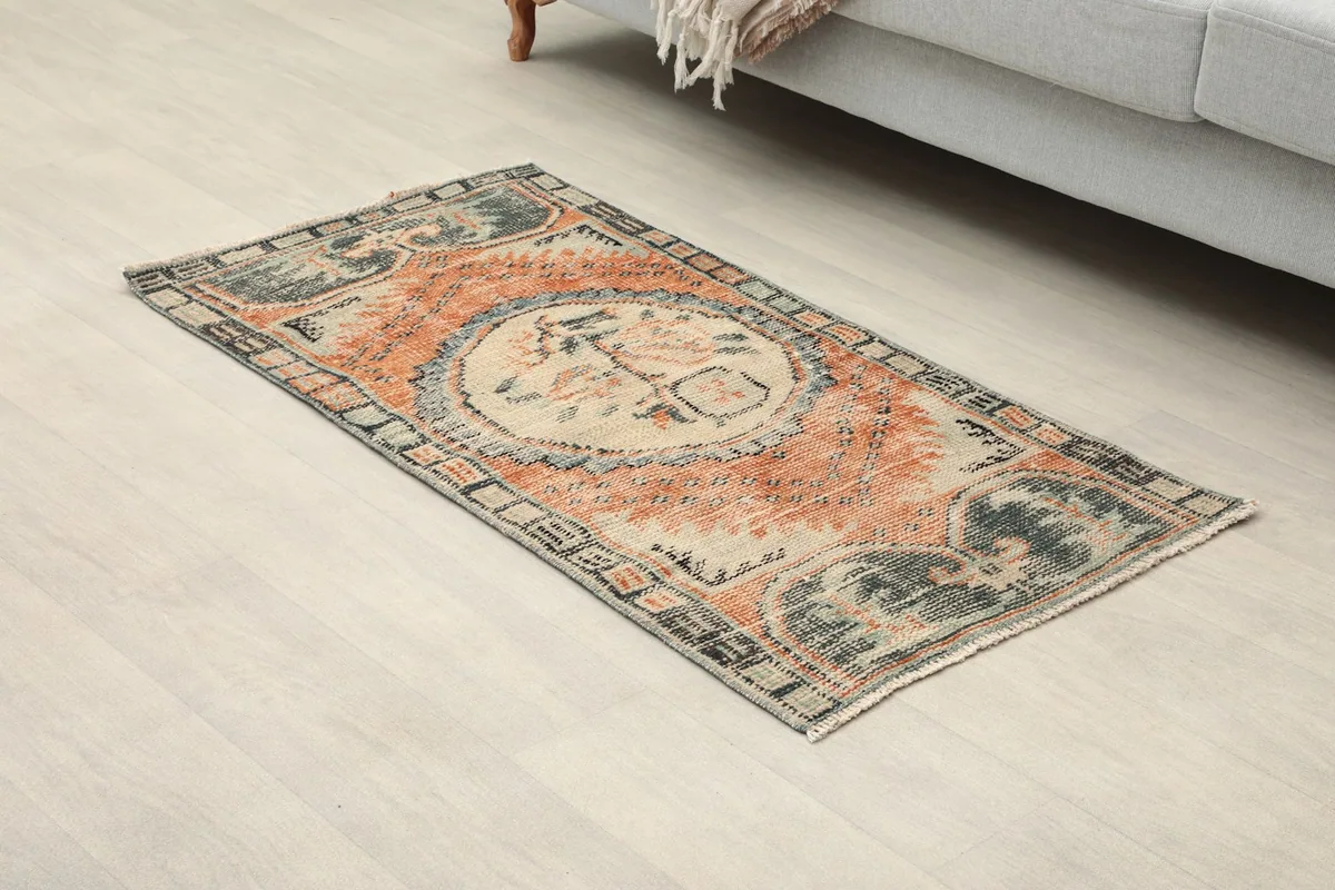Angled view of the rust and ivory rug, showing its full design and colors