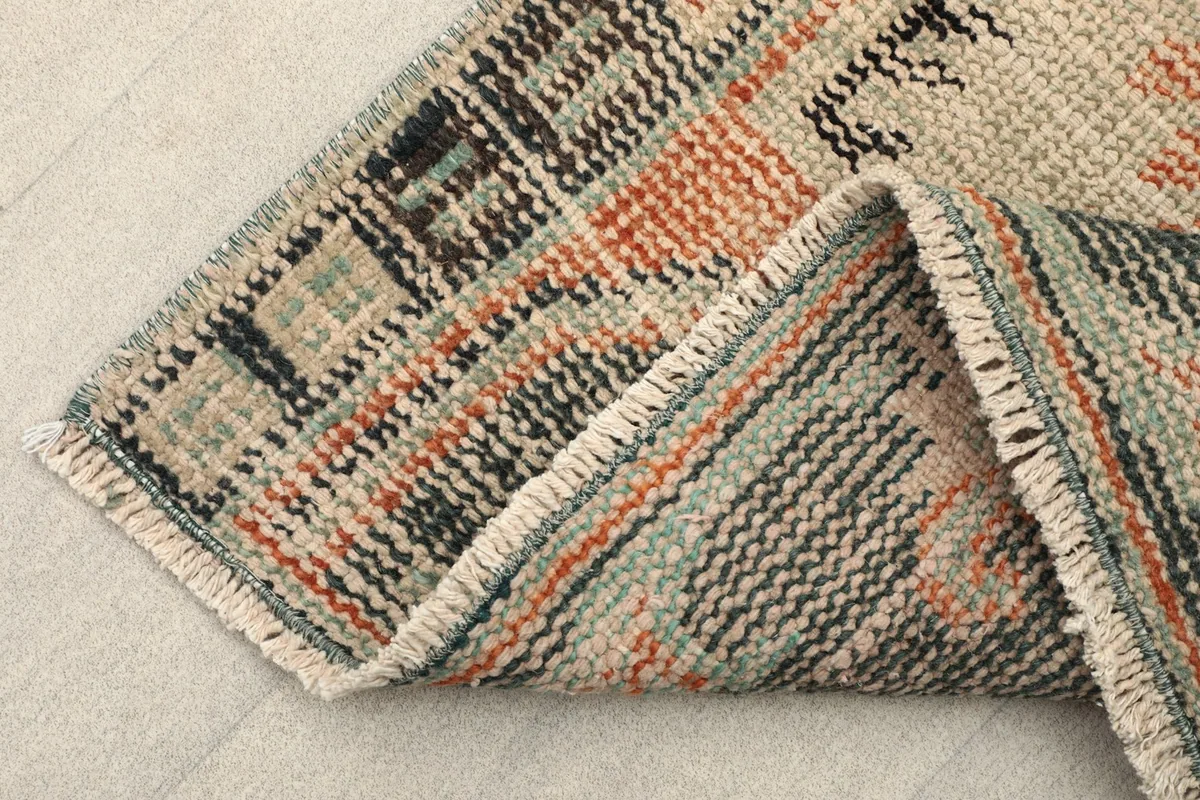 Folded corner of the rug, showing the wool pile and cotton foundation from the side