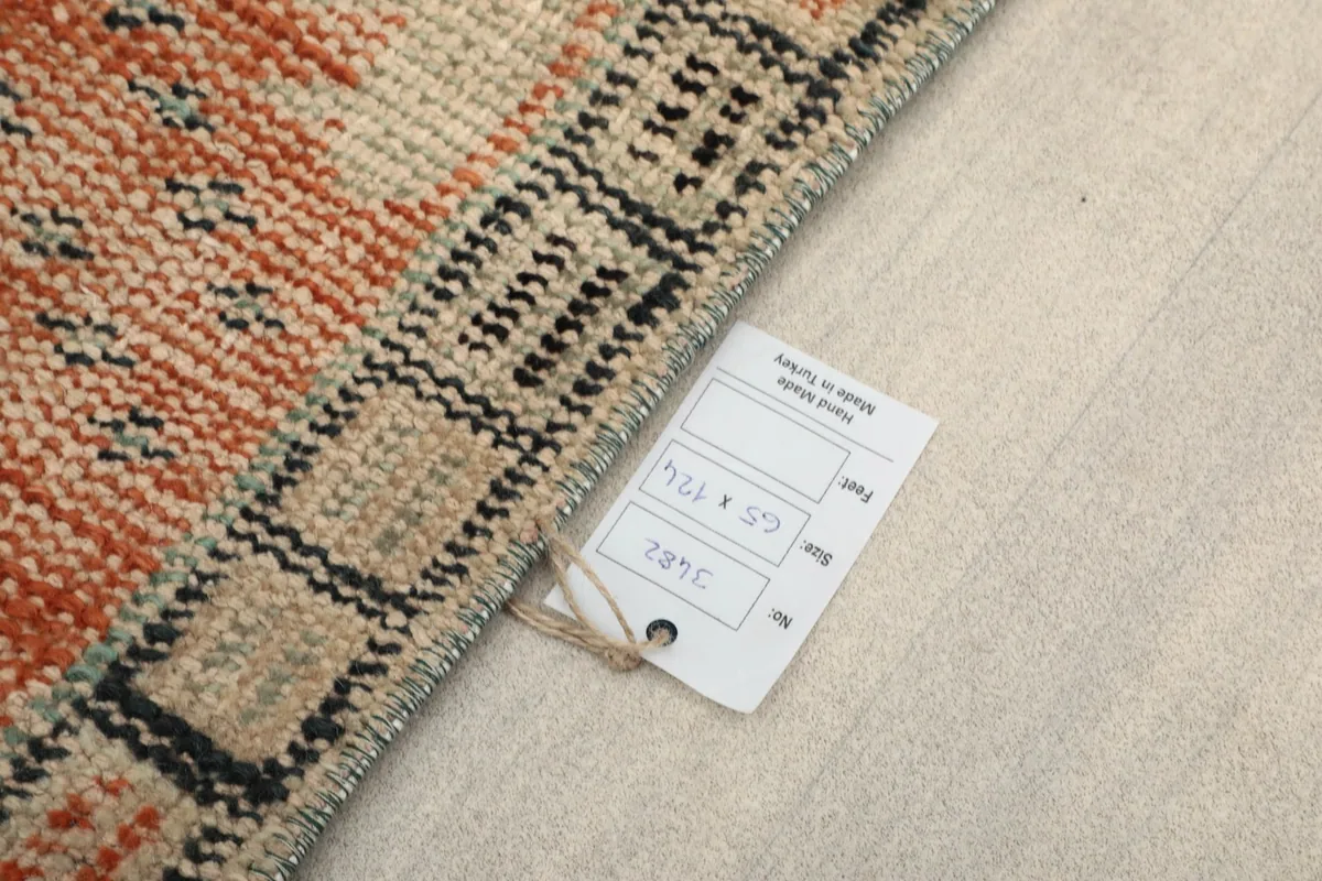 Rug tag showing the dimensions 65 x 124 cm, attached to the corner of the rug