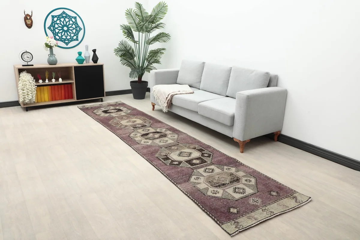 Long view of the vintage runner rug in a contemporary living space with a gray sofa and wooden cabinet