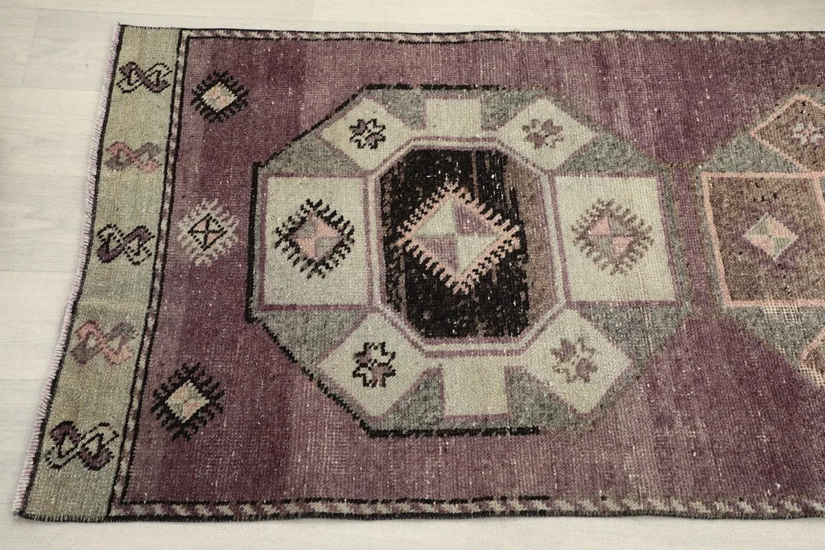 Detailed view of the geometric medallion and border design, highlighting the rose, black, and beige colors