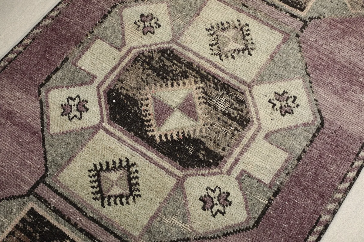 Overhead close-up of a central geometric medallion with intricate details in rose, black, and beige tones