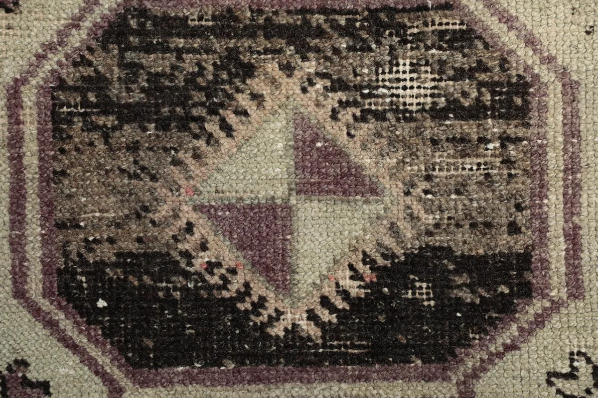 Extreme close-up showing the low wool pile and distressed texture of the hand-knotted vintage rug