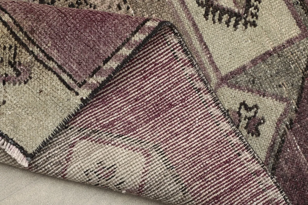 View of the rug's back, showing the hand-knotted construction and cotton foundation with a folded edge