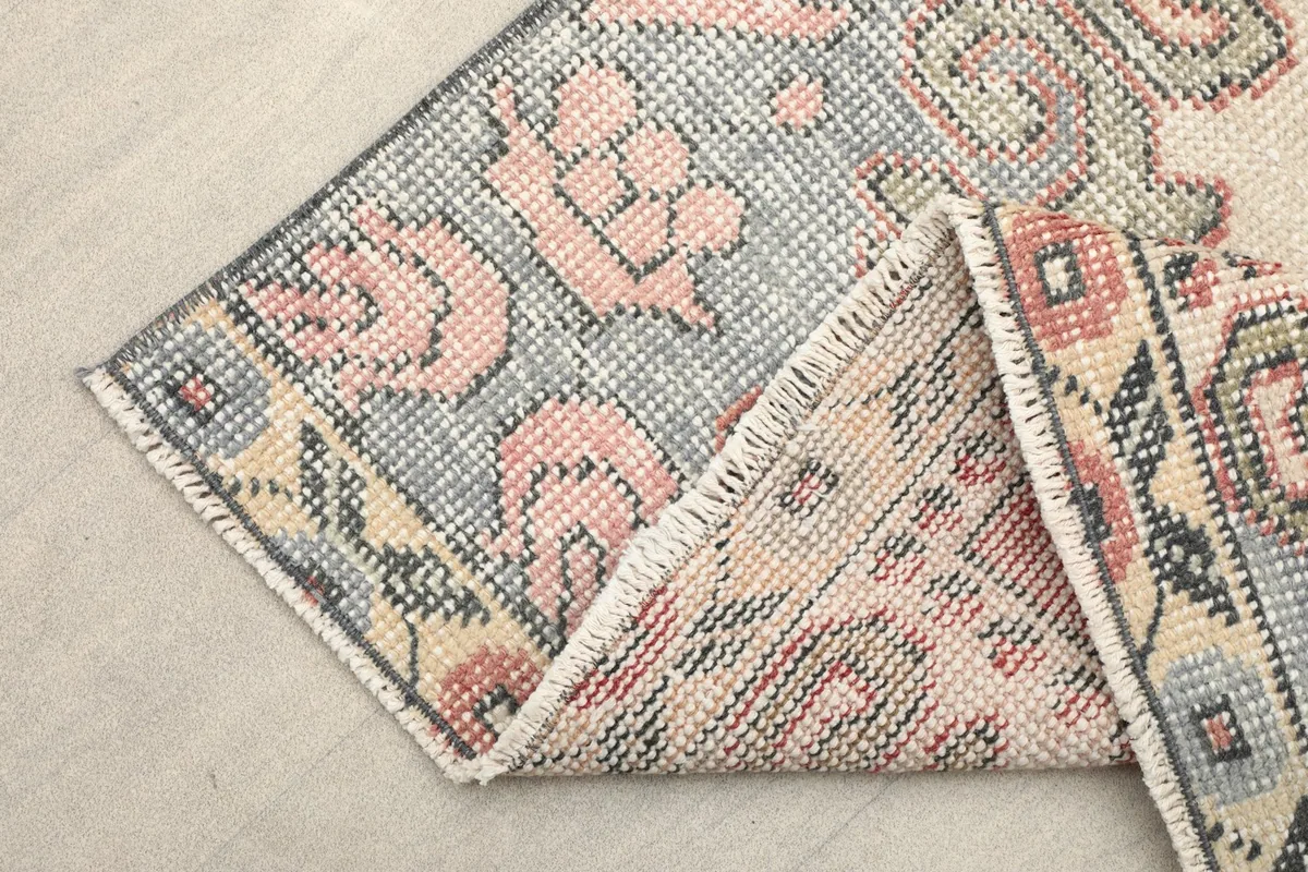 Folded corner of the rug revealing the cotton foundation and tight knotting.