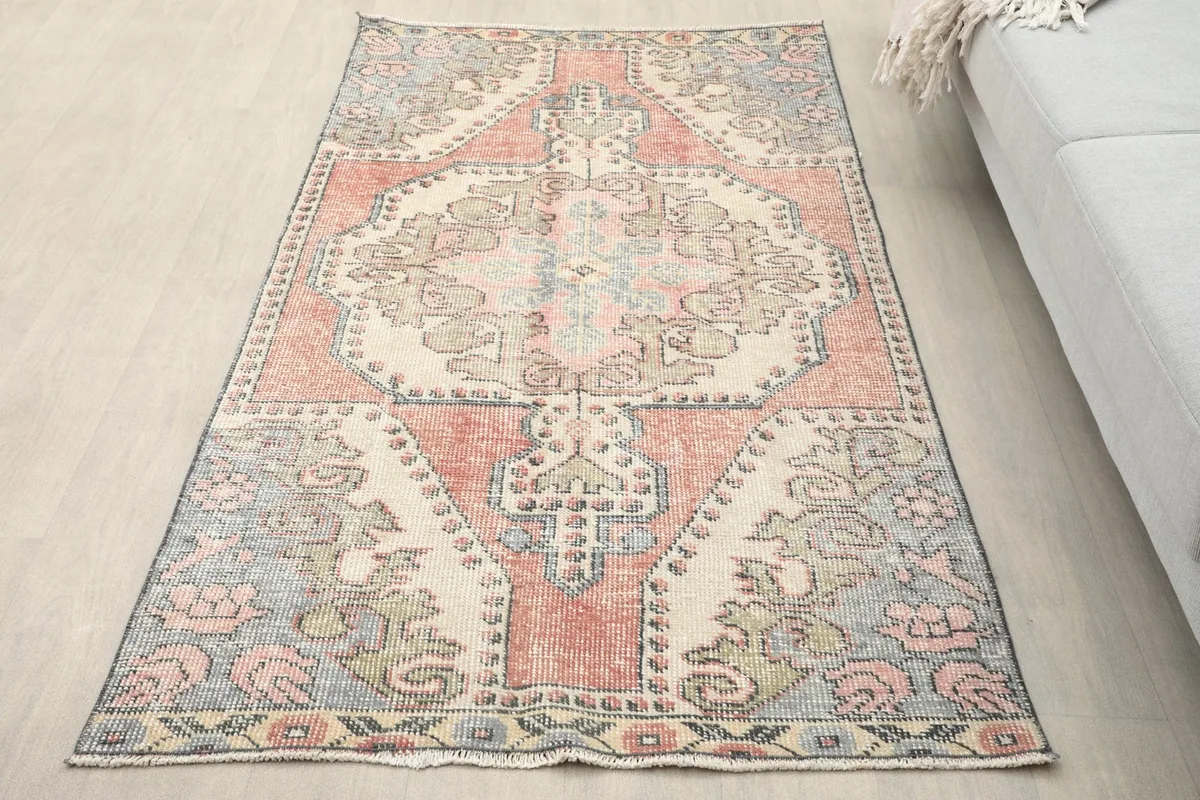 Overhead view of the vintage rug on a light floor, showing its full design and colors.