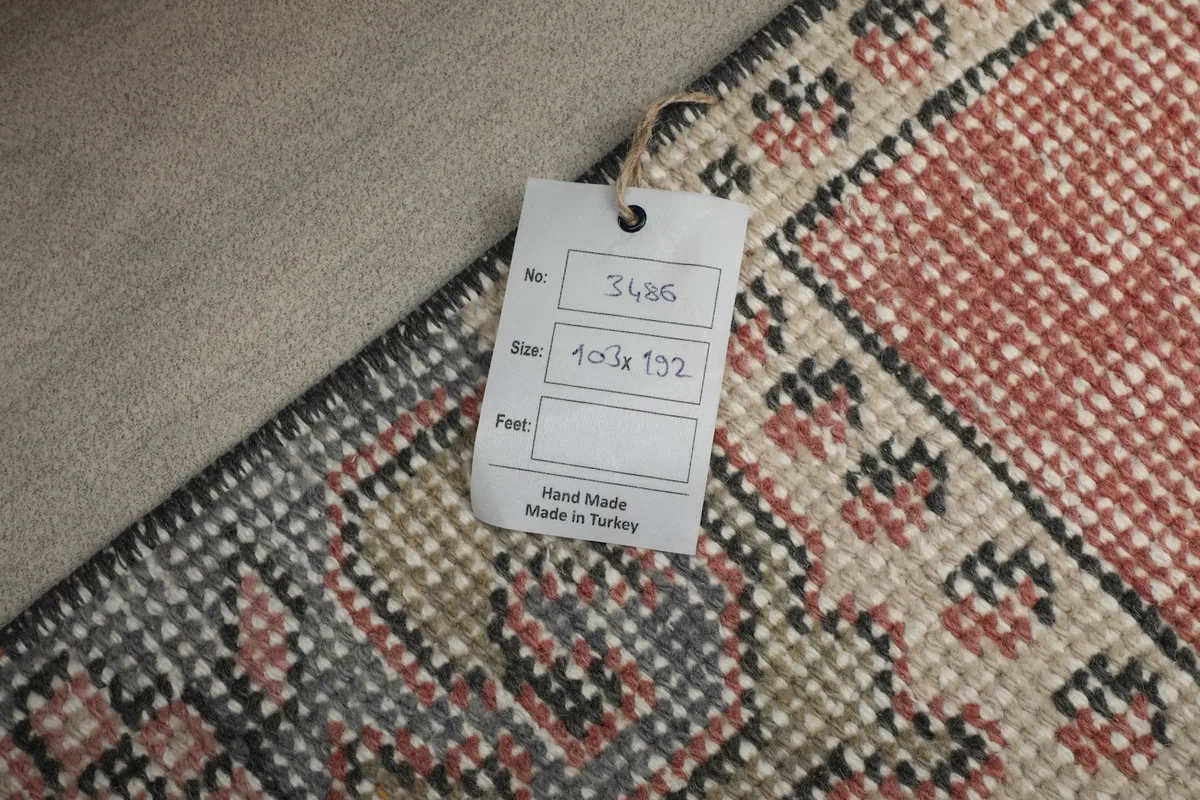 A tag attached to the back of the rug, indicating its handmade origin and size.