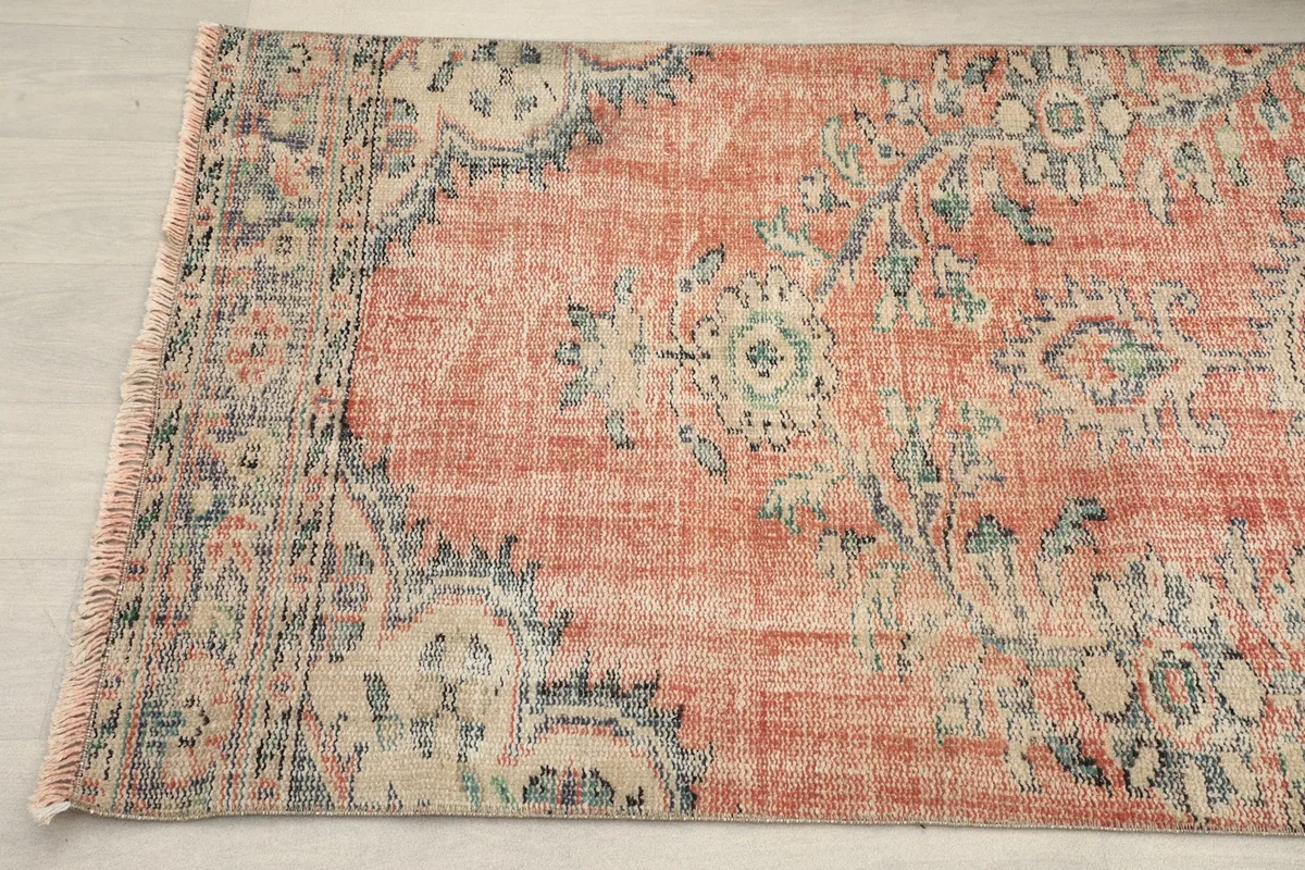 Detail of the rug's opposite border and corner, showcasing the vintage patina