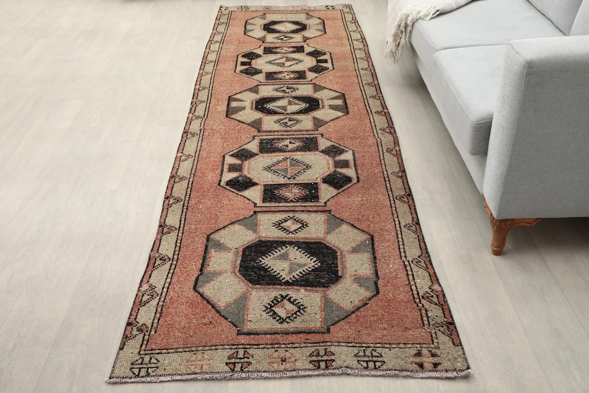 Runner rug displayed in a room setting, showing its length and colors next to a sofa