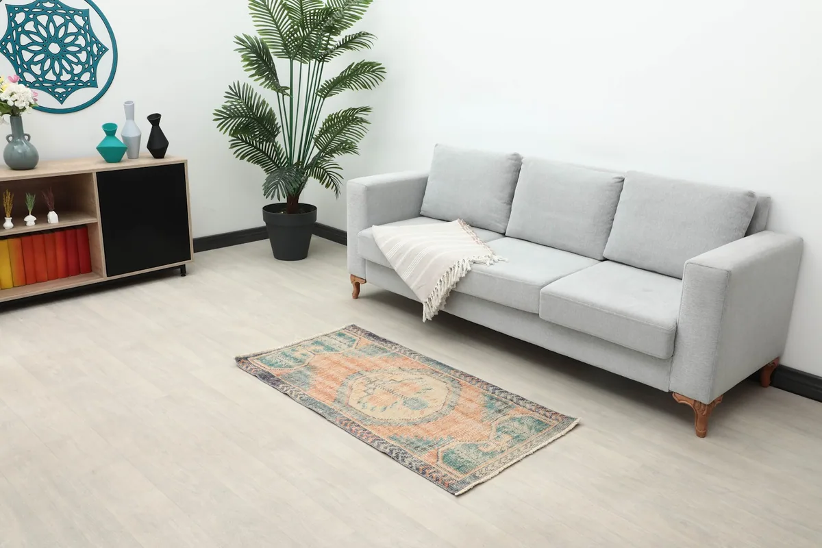 Vintage Anatolian rug placed in a living room setting under a gray sofa