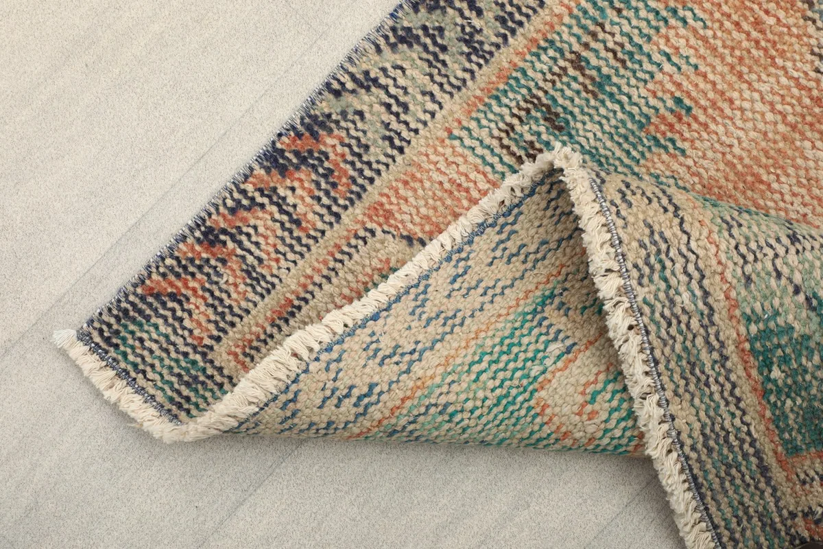 Corner of the rug folded to show the thickness and flexibility of the vintage textile