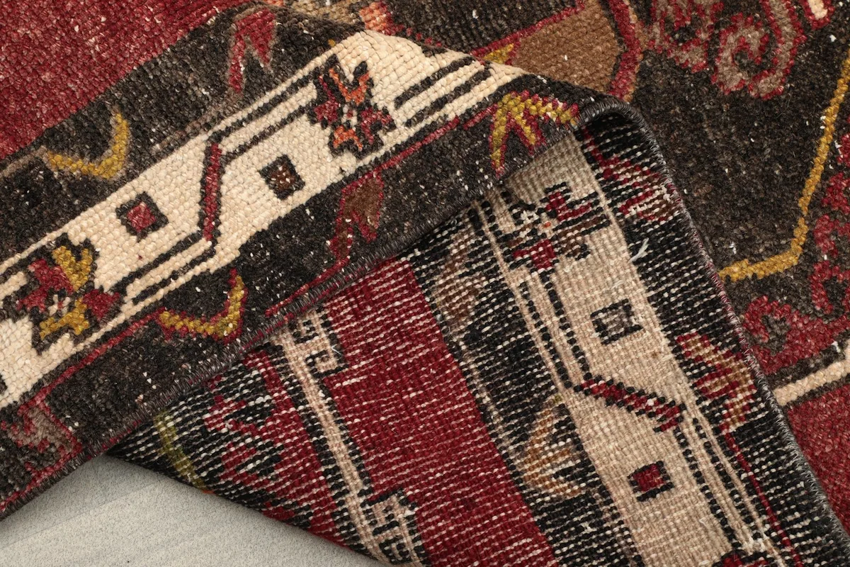 Close-up of the folded rug edge, revealing the hand-knotted construction and fringe