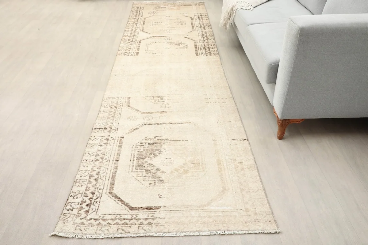 Beige and brown runner rug in a living room setting next to a light gray sofa